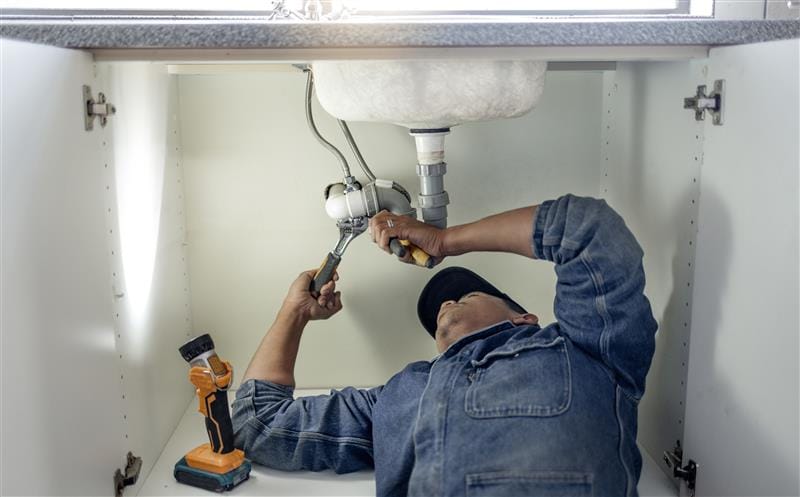 Plumber repairing pipes beneath a bathroom sink in Citrus Heights